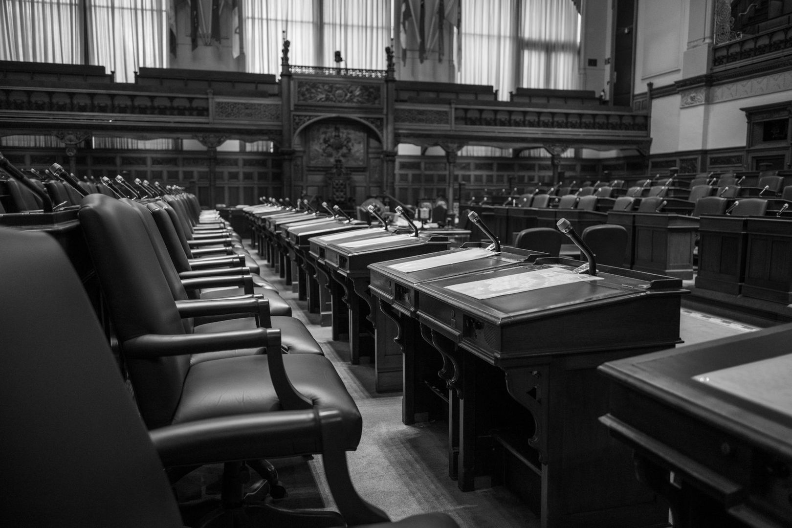 Empty parliamentary chamber with rows of desks, chairs, and microphones
